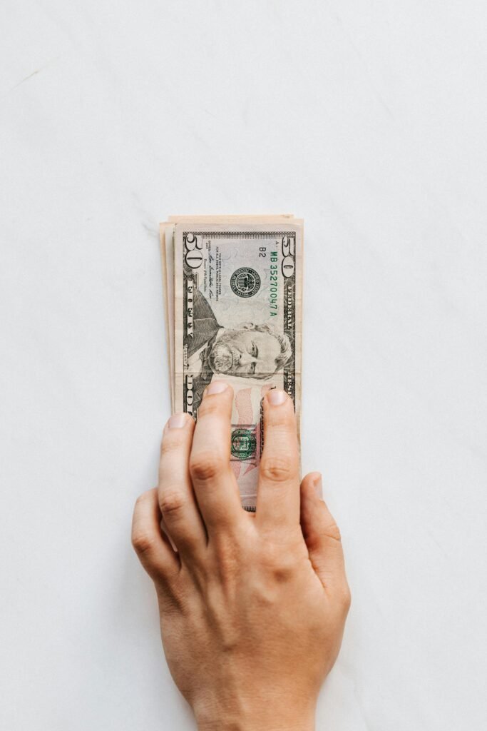 A hand holds a stack of US dollar bills, symbolizing wealth and finance.